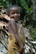 Pygmy child next to a leaf hut